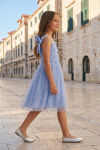 Rina girls' light cornflower blue dress – girl on an old town street, full-length profile