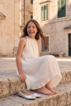 Rozalia white pleated dress outdoors – seated on stone steps