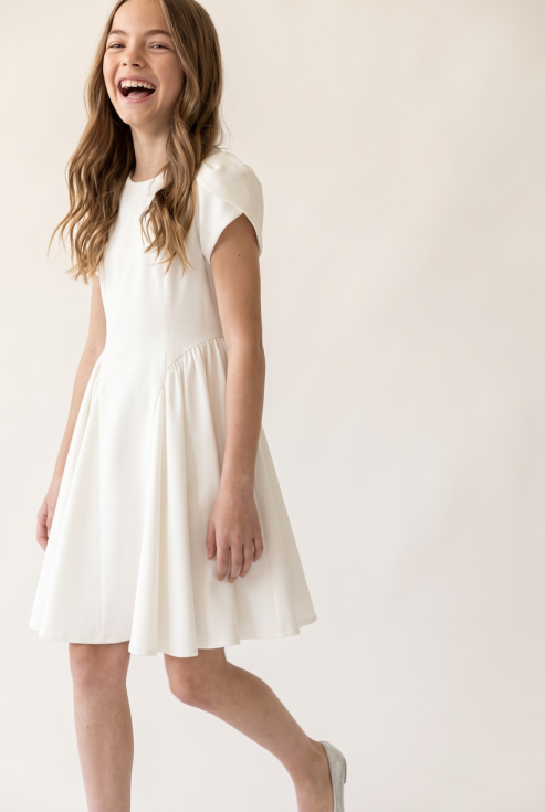 Rumi girls' white dress with tulip sleeves – smiling girl in motion, front view
