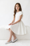 Rumi girls' white dress – seated on a white bench, front view