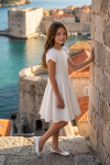 Rumi white dress with tulip sleeves – outdoors by a stone wall